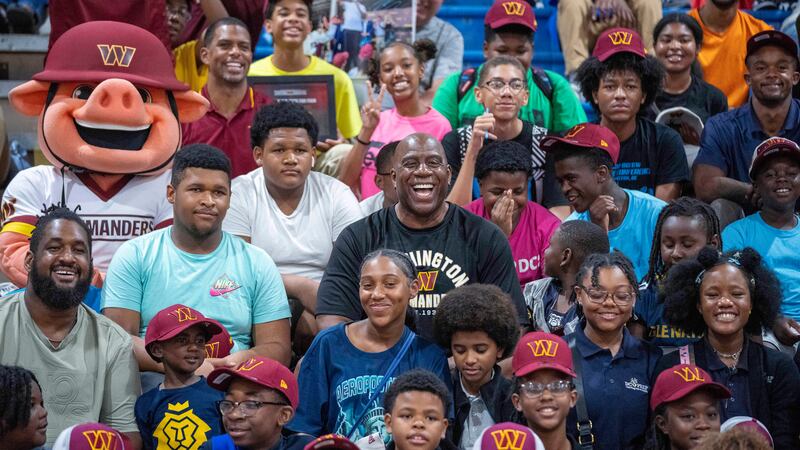 Washington Commanders part-owner Magic Johnson, center, poses for a photo in the stands with...